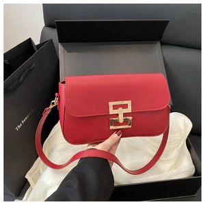 Detailed view of red leather crossbody bag with gold metal buckle in elegant gift box
