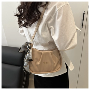 Détail du sac à bandoulière plissé beige avec foulard géométrique et lettrage doré imprimé