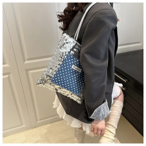 Detail of silver sequin tote bag with blue polka dot denim pocket and logo