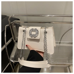 Détail du sac à bandoulière en cuir blanc avec chaîne argentée et boucle strass