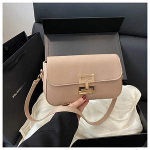 Close-up of beige crossbody bag with premium gold clasp on luxury silk gift packaging