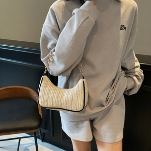 Minimalist beige woven underarm bag with gold chain strap worn with casual grey outfit