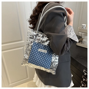 Detail of silver sequin tote bag with blue polka dot pocket and AGOGO logo on strap