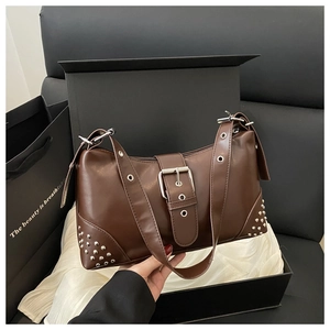 Détail du sac à main en cuir marron foncé avec clous argentés en boîte cadeau