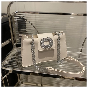 Détail d'un sac carré en cuir crème avec une grande boucle en strass étincelants et chaîne