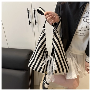 Close-up of black and white striped canvas tote bag with a white lace bow detail