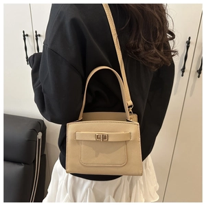 Detail of light beige Saffiano leather bag showing golden lock and crossbody strap