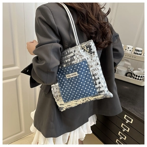 Detail of silver sequin tote bag with a blue polka dot pocket worn with a grey blazer