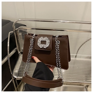 Détail d'un sac à main en cuir marron foncé avec boucle ronde en strass et bandoulière