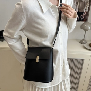 Sac bandoulière noir minimaliste avec boucle en métal argenté porté par un mannequin
