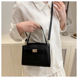 Detail of black Saffiano leather handbag featuring a golden turn-lock closure and shoulder strap
