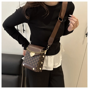 Détail du sac bandoulière marron à motif vintage avec chaîne dorée et breloque coeur