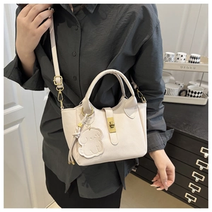 Detail der beigen Beuteltasche mit Litschi-Maserung, Drehverschluss und Hundeanhänger