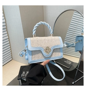 Detail der Tasche aus blauem Leder und Stroh mit goldener Blumenschnalle und Flechtgriff