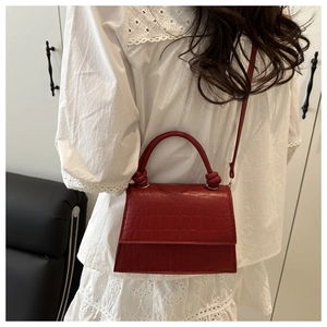 Detail view of red crocodile-embossed leather crossbody bag on a model with lace top
