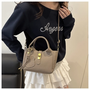 Détail du sac seau taupe pour femme avec fermoir rotatif métallique et pendentif floral