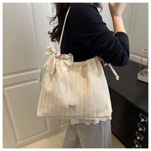 Detail of hand-woven straw bucket bag with floral lace bow and metallic logo accent