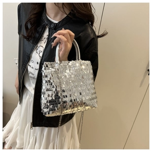Detailed close-up of a silver sequined tote bag with metal chain strap on a model