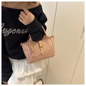 Détail du sac seau rose avec texture litchi, fermoir doré et accessoire d'ours