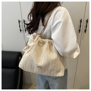 Detail of beige woven tote bag with silver bow accent and floral embroidery scarf