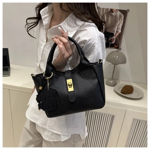 Détail du sac seau en cuir grainé noir avec fermoir doré et breloque ours en peluche