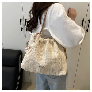 Detail of straw woven bucket bag featuring embroidery silk scarf and silver bow detail