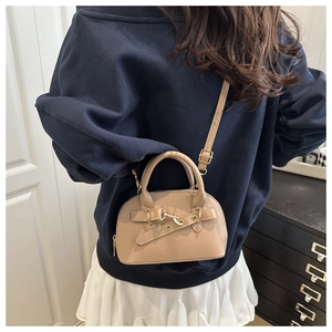 Beige mini shell shoulder bag with adjustable strap worn with a modern casual outfit