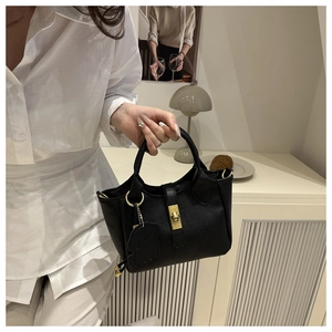 Détail du sac seau noir en cuir grainé avec fermoir rotatif doré et charm en forme d'ourson