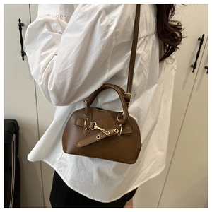 Brown leather shell bag detail featuring gold metal hardware and adjustable crossbody strap