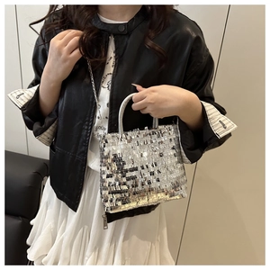 Detail of silver sequin tote bag featuring round handles and polished metal chain strap