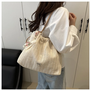 Detail of beige straw bucket bag with floral lace scarf and silver bow charm