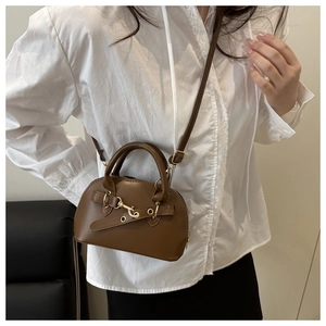 Detailed view of a vintage brown shell bag styled with a white shirt and black skirt