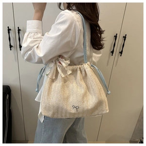 Detail of straw woven bucket bag with blue drawstring and floral lace scarf decoration