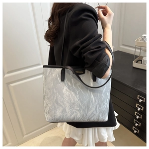 Detail of silver-grey tote bag showing its unique crinkled paper texture and black label