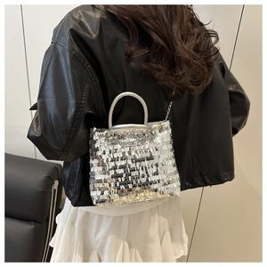 Detail of silver sequin tote bag with chain strap worn with a black leather jacket