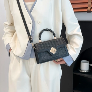 Schwarze gewebte Umhängetasche mit goldenem Verschluss an weißem Blazer-Outfit