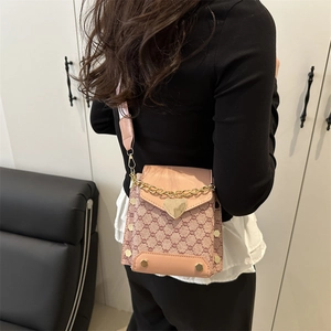Petit sac bandoulière rose au motif vintage avec boucle cœur dorée porté par un mannequin