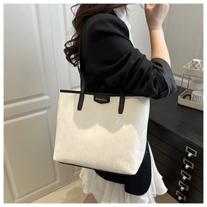 Detail of white wrinkled leather tote bag with black straps and fashion label tag