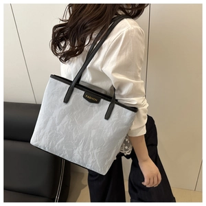 Detailed texture of white crinkled tote bag with black strap and fashion leather tag