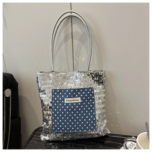 Detail of silver sequin tote bag with blue polka dot pocket and brand label