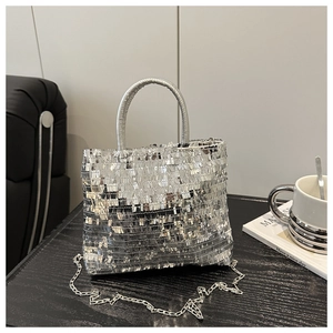 Close-up of shiny silver sequined tote bag with chain strap on a dark wooden table