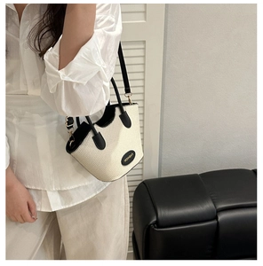 Detail of cream woven bucket bag with black PU handles shown in a lifestyle setting