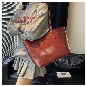 Close-up of vintage dark red tote bag with glossy pleated texture and long handles