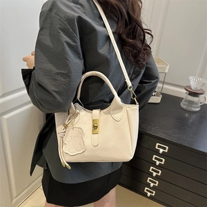 Sac seau chic en cuir beige avec charm de chien et pendentif M doré sur la bandoulière