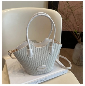 Detailed shot of white woven bucket bag with leather handles and gold fashion logo