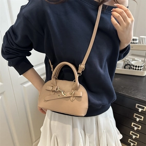 Chic solid color shell handbag with adjustable shoulder strap shown in lifestyle setting