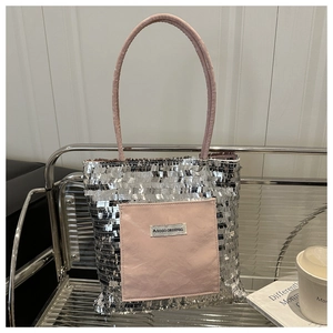 Detail of silver sequin tote bag with pink leather pocket and AGOGO logo on a chair