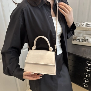 Chic beige crocodile pattern square crossbody bag worn by a model in black and white attire