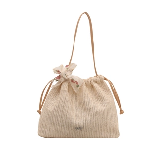 Chic beige straw bucket beach bag with drawstring closure and floral scarf accent