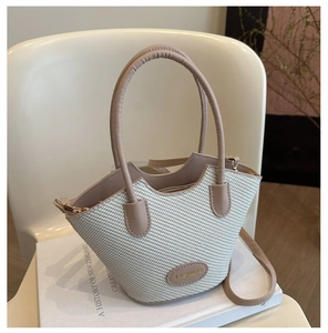 Detailed view of beige woven bucket bag with pink leather trim and round handles